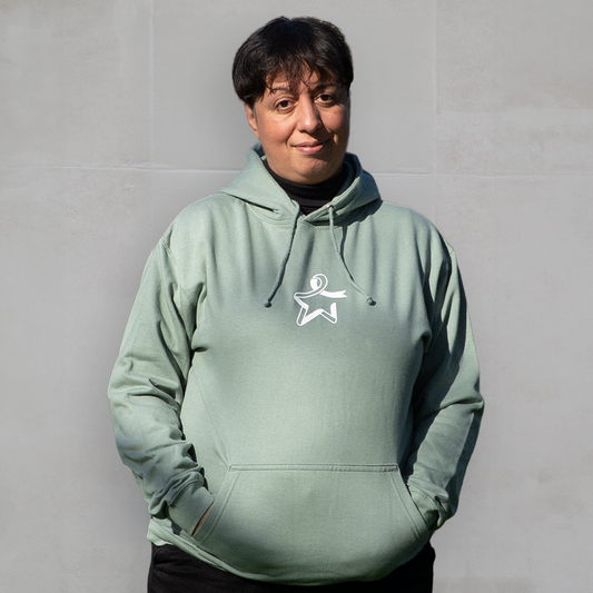 Female model wearing a green hoodie, standing against a grey background. The hoodie features a white Star of Hope printed on the front.